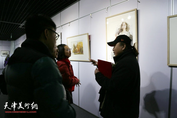 图为朱志刚在画展现场向观众介绍作品。