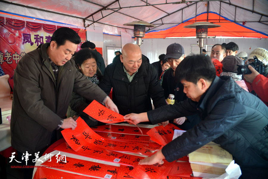 图为天津楹联协会会长陈伟明在活动现场为居民送对联。