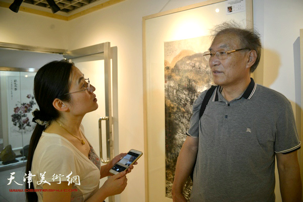 图为何延喆、孙辉在画展现场交流。