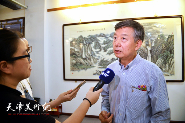 吴长江在画展现场接受媒体的采访。