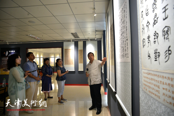 马魏华向记者介绍汉字衍化发展史书法展的作品。