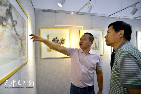 吴振江向天津西青区美协主席李桂金介绍展出的作品。