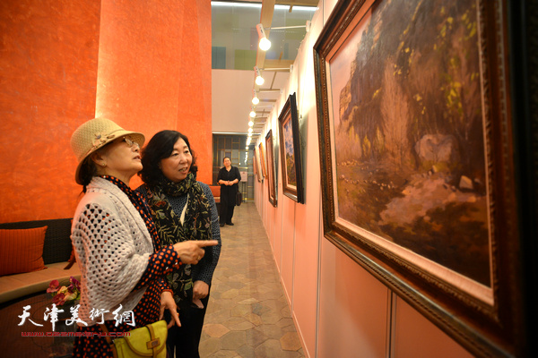吴薇、焦小红在观赏展出的风景油画作品。