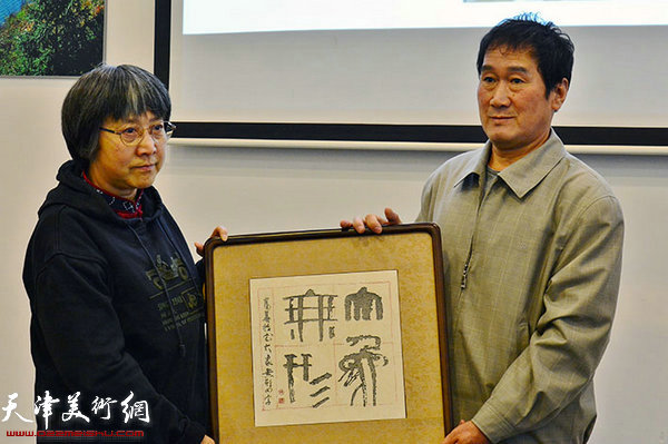 韩富华夫人接受书画爱好者赠送的石刻作品。