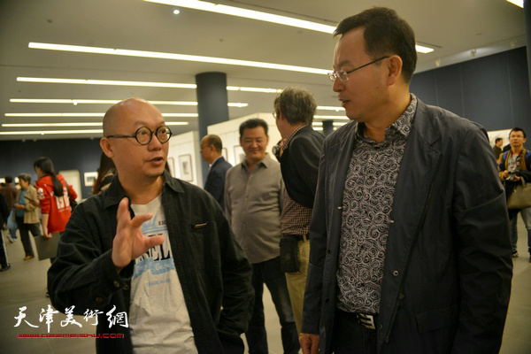 张桂元与画家唐道一在画展现场交流。