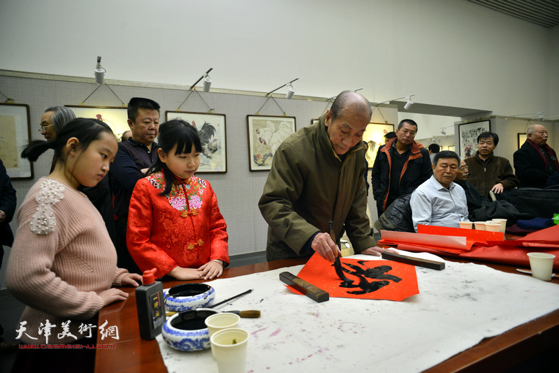 刘正明在画展现场为观众送“福”。