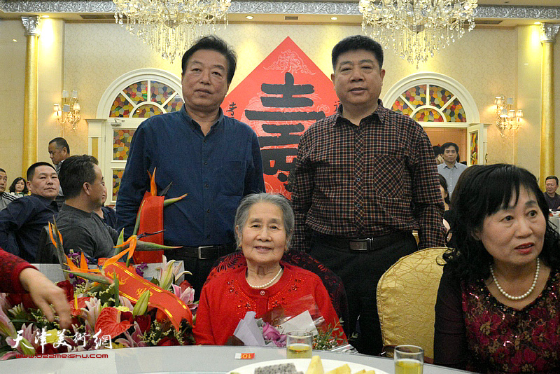 杨建国、张养峰与肖培金的老母亲高连荣在写大吉精品展现场。