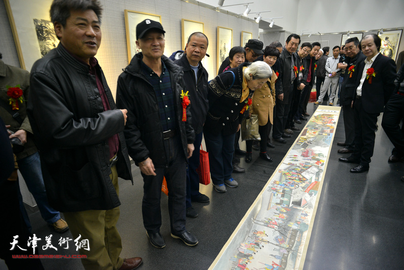 来宾在画展现场观赏刘维仑的《盛世集贸图》和《盛世闹春图》长卷。