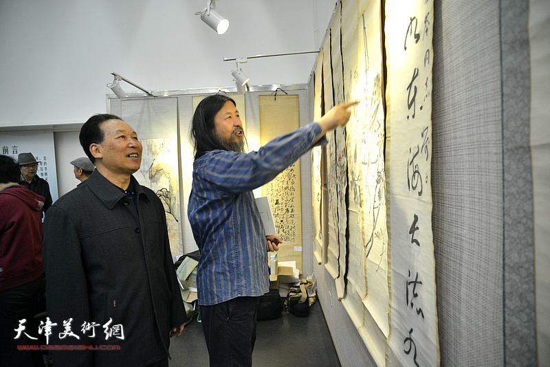 刘传光、梁旭华在观赏展出的书画作品。