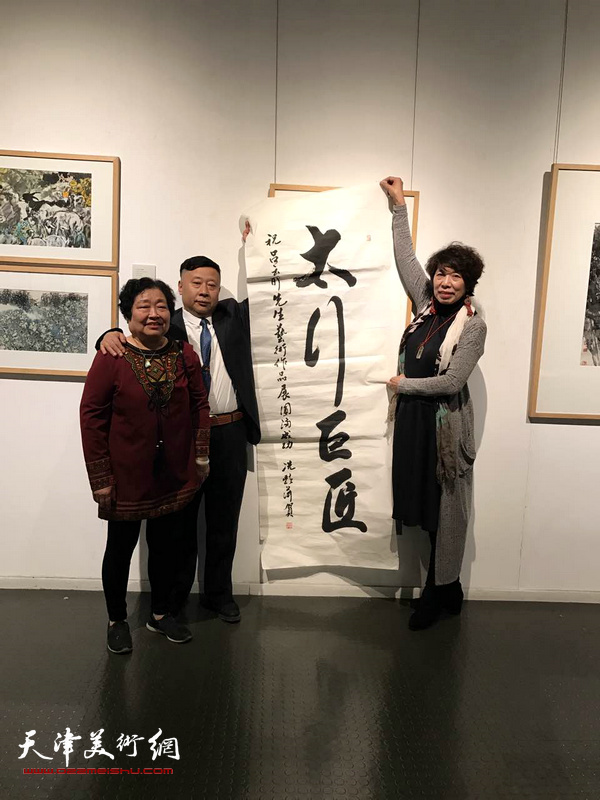 吕大江、张秀茹、吕爱茹在画展现场展示著名女书法家冼艳萍为画展题写的贺词：太行巨匠。