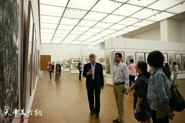 申世辉陪同各行业来宾观赏展出的作品。