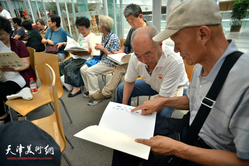 观众在画展现场阅读《素心若雪-肖培金中国画》画集。