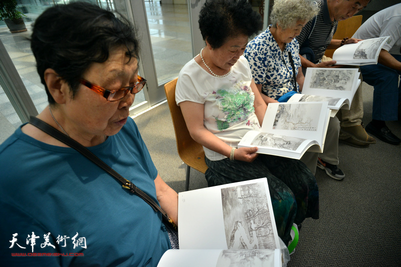 观众在画展现场阅读《素心若雪-肖培金中国画》画集。