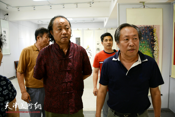 西沽书画院秘书长卢勇陪同刘国胜观赏展品。