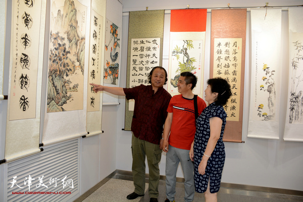 卢勇、杜秀兰、王鸿霖在观赏展出的画作。