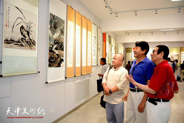吴克义、周学忠在观赏展出的画作。