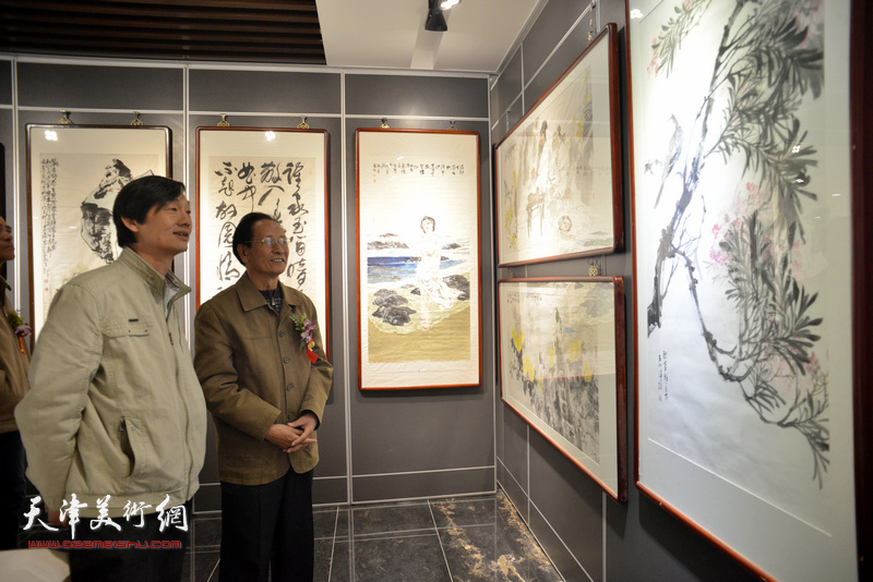 郭金标、徐庆荣在观赏展出的画作。