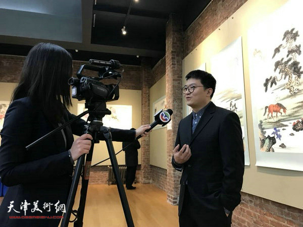 伯骧在画展现场接受当地媒体采访。