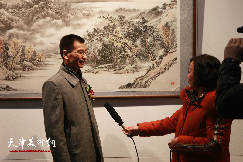 姜金军在画展现场接受媒体采访。