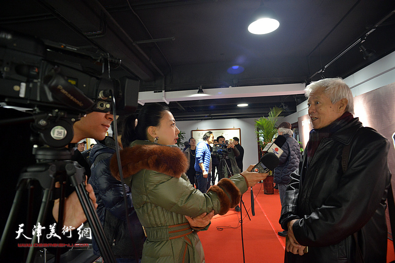 陆福林在画展现场接受媒体的采访。