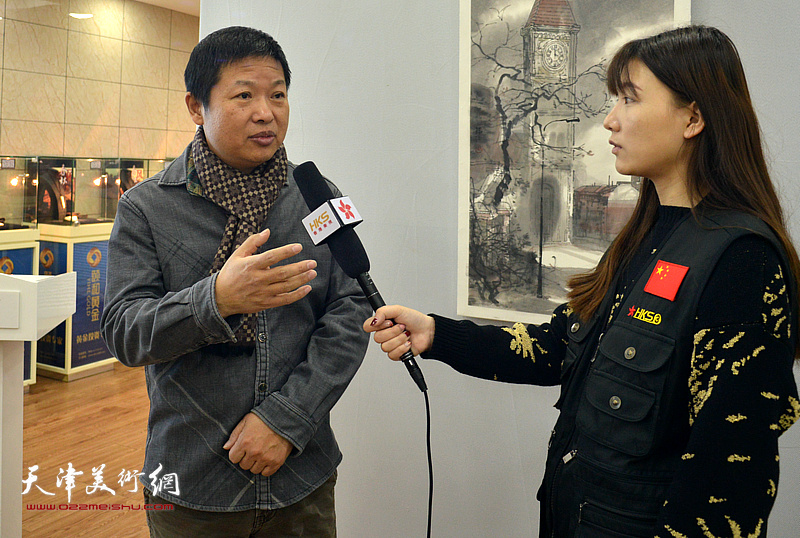 魏瑞江在画展现场接受媒体的采访。