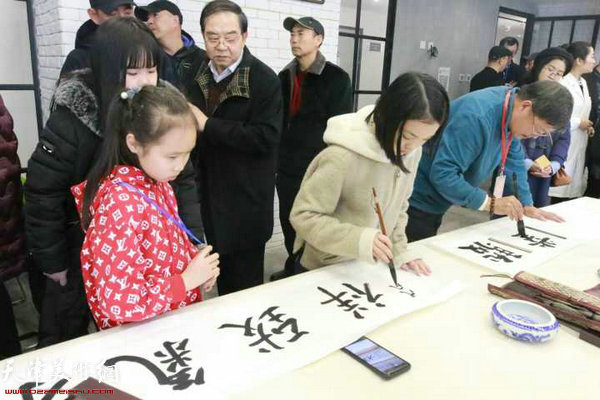 学习书法的小同学在联谊会现场写字。