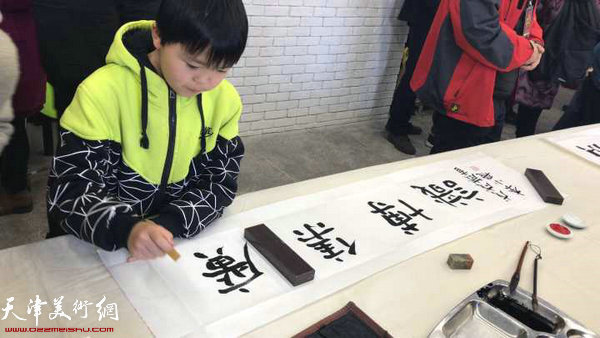 学习书法的小同学在联谊会现场写字。