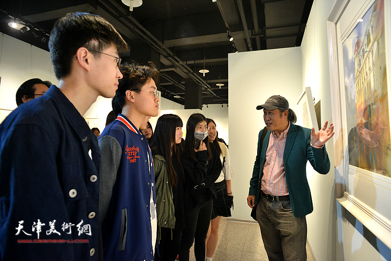 王刚在画展现场为大学生们讲解水彩艺术。