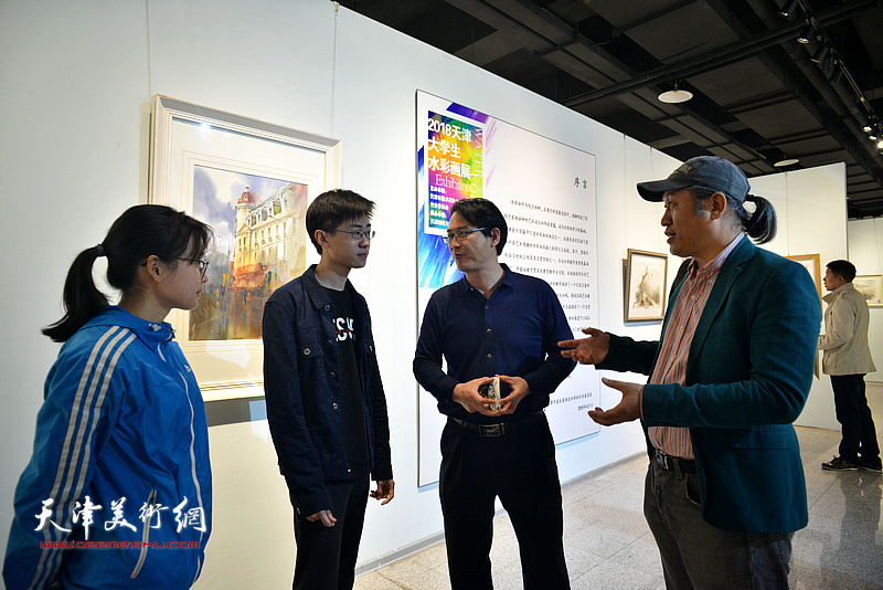 王刚、滑寒冰与参展作者在画展现场交流。