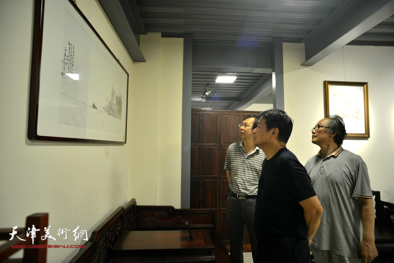 刘文生、陈福春、刘文生、路洪明在画展现场观赏展品。