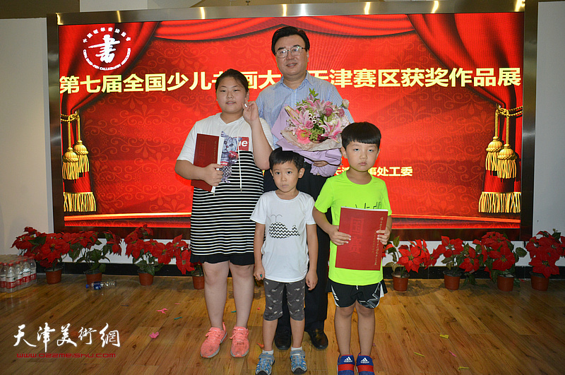 中国硬笔书法协会主席张华庆与获奖小艺术家们在画展现场。