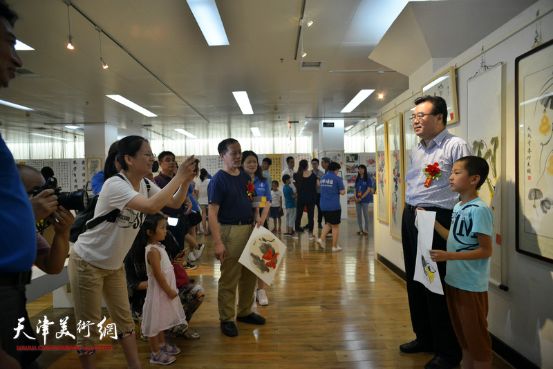 中国硬笔书法协会主席张华庆与小艺术家在画展现场。