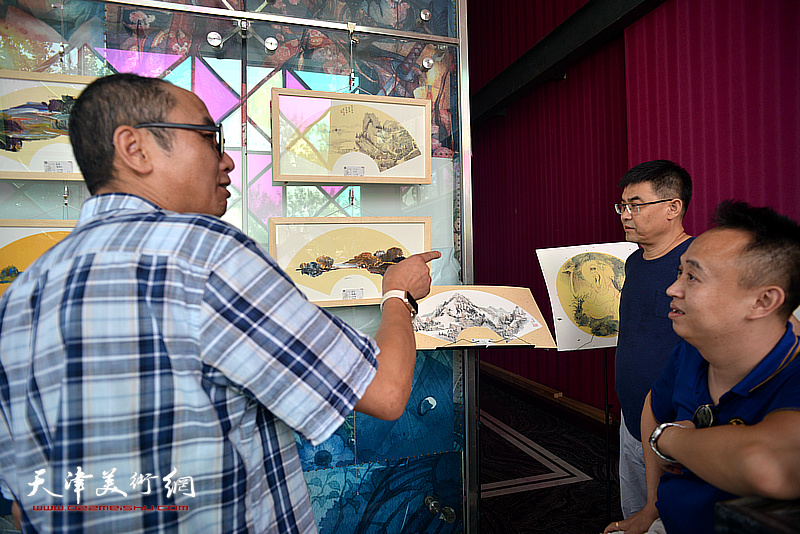 马霑、李建良、马明在画展现场交流。