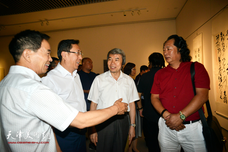 王禹、孙敬忠与参展画家刘长龙在画展现场交流。