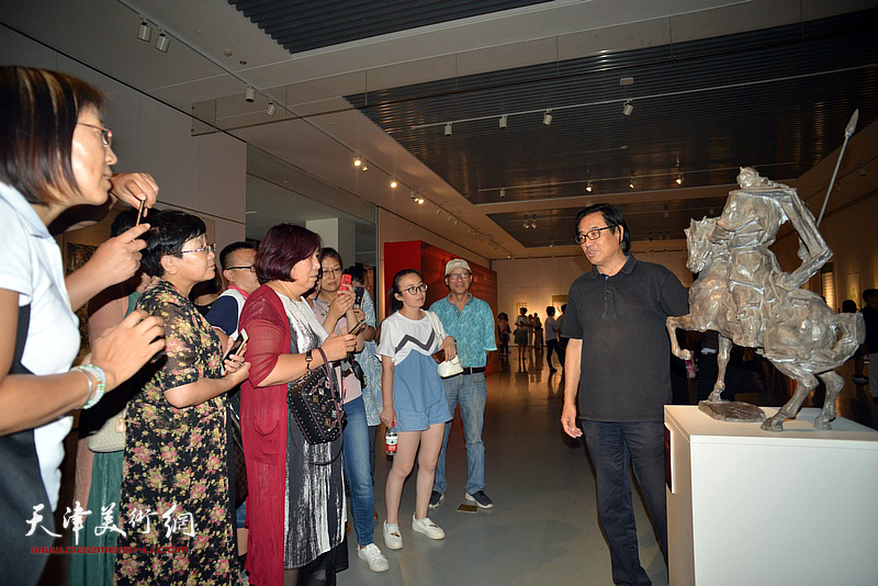 景玉民在展览现场向观众介绍他的雕塑作品。
