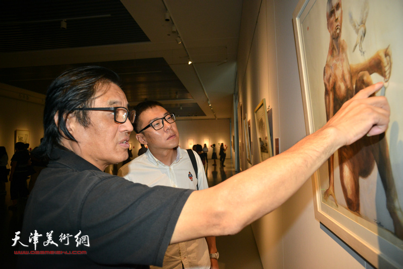 景玉民在展览现场为参展画家指点作品。