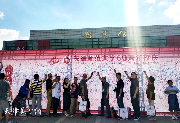 图为城市画派画家在天津师范大学建校60周年纪念墙上签名。