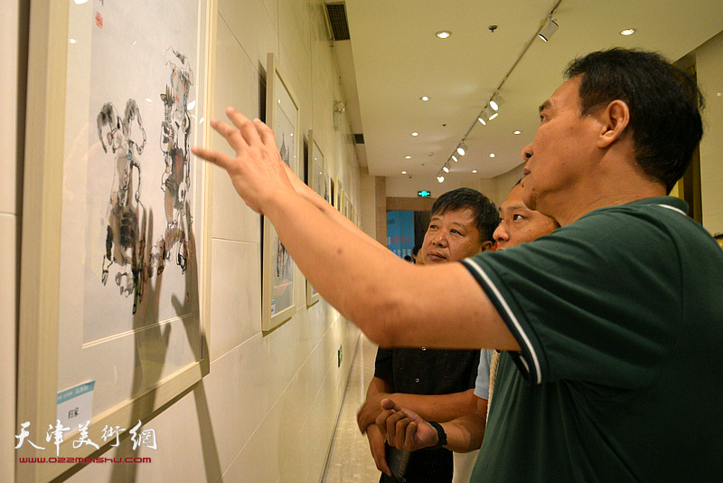 马寒松、宋新勇、姚铸在观赏展出的画作。