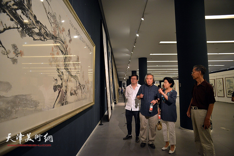 曹秀荣、刘建华、霍春阳在画展现场观看作品。