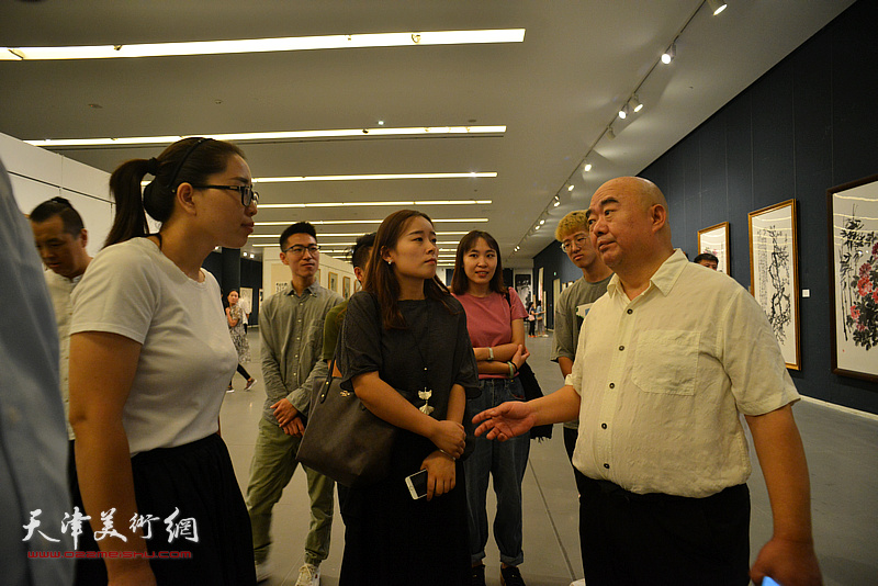 尹沧海与韩晓娜等学生在画展现场交流。