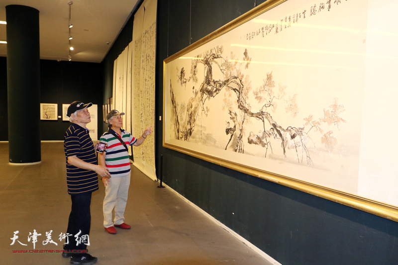 纪振民、姬俊尧在画展现场观看作品。