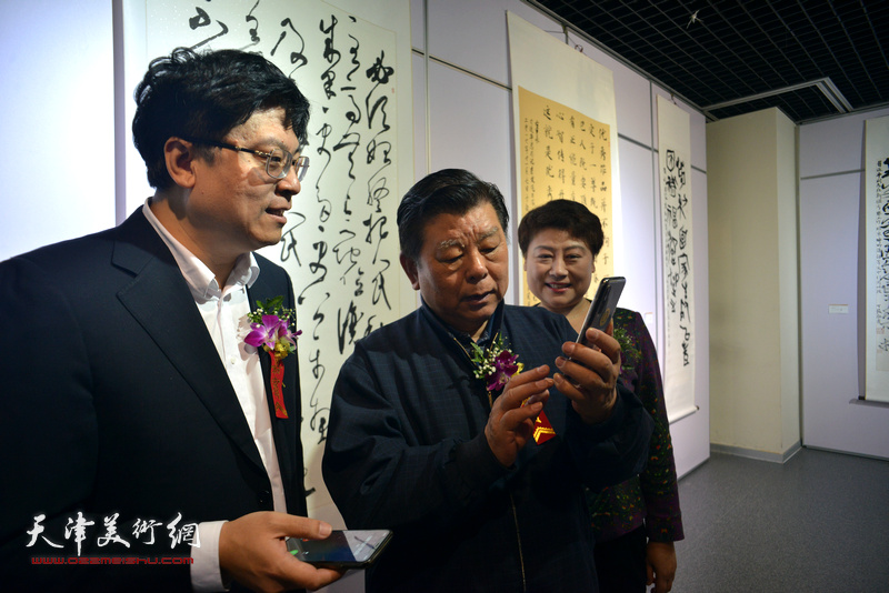 胡振民、寇江华、王平在观赏手机拍摄的作品。