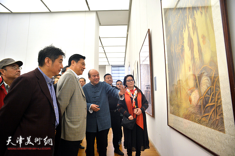 孟庆占陪同董伟观赏展出的作品。