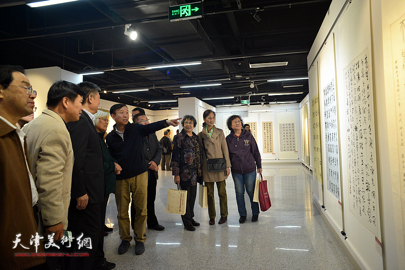张建会在展览现场与参展作者、观众观赏作品。