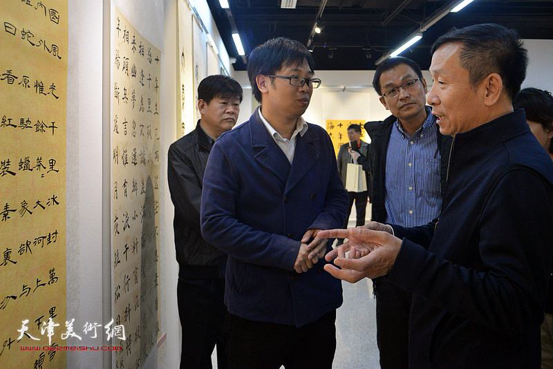 张建会在展览现场为参展的青年作者张健、刘金伟点评展品。