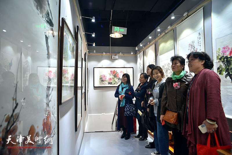 女画家们在画展现场观看作品。