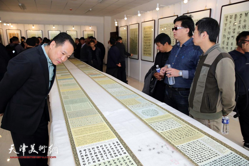 图为观众在仔细欣赏《汉字衍化与书法发展——临写作品》手卷