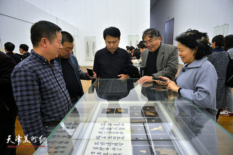 张洪春、唐镁、沈蕴杰在展览现场观看展出的甲骨文实物。