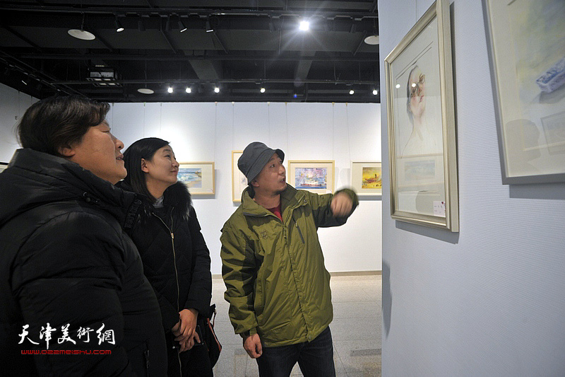 姜中立、路学正、张蓉在画展现场讲解作品。