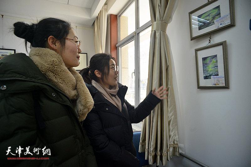 参展教师李梦羲在观看展出的画作。